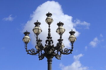 Fototapeta na wymiar St Peter's Square Historic Streetlight Detail Against a Bright Blue Sky with Clouds in Rome, Italy