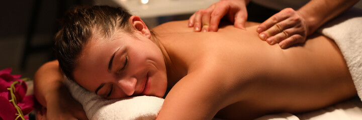 Smiling woman masseur doing back massage at spa center