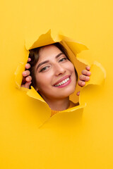 Optimistic woman peeking from hole in paper