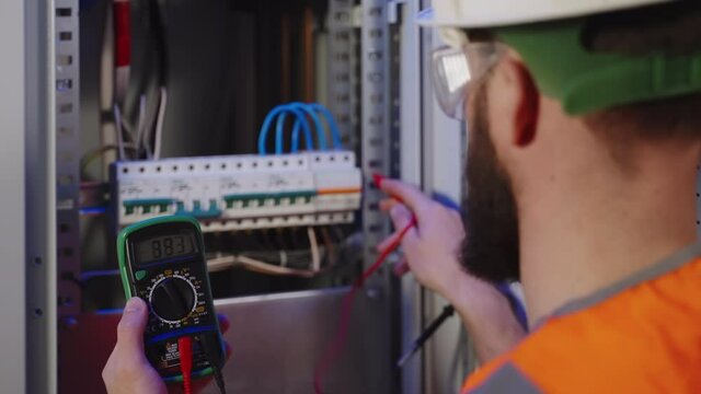 Electrician using multimeter to check switchboard
