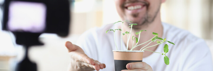 Smiling man demonstrates seedlings on video camera