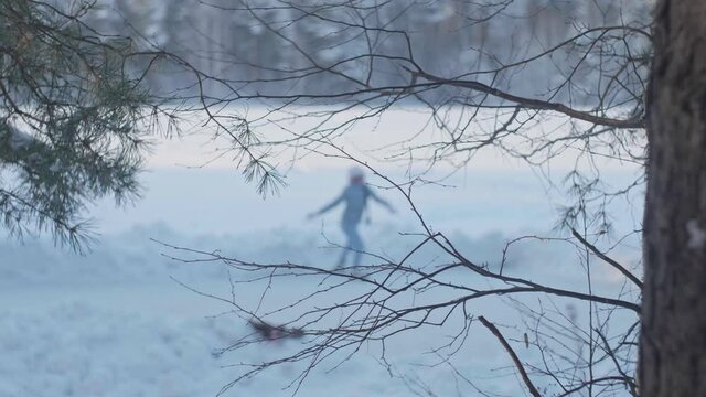 A girl skates on a frozen lake in defocus in the winter forest. Figure skating. Footage for the substrate