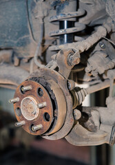 Rusty rear hub brake pads on an old car. In the garage, a man changes parts on a vehicle. Small...