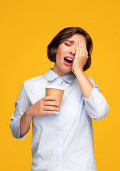 Tired woman rubbing eyes while having coffee