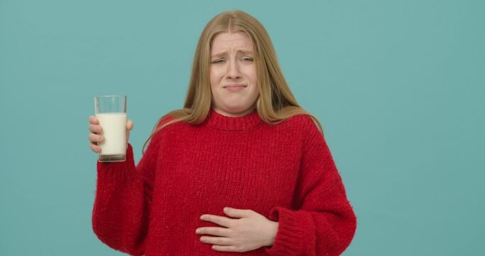 Young woman with long blond hair dressed in a red sweater suffers from lactose intolerance