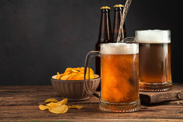 Pouring chilled beer into beer mugs on a dark brown background.