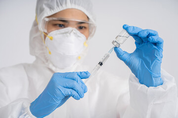 Doctor wearing a medical mask holds a syringe containing a vaccine to treat coronavirus.