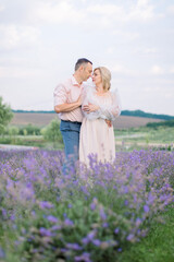 Fototapeta na wymiar Love, silver wedding anniversary. Happy romantic mature Caucasian couple, posing together looking each other, while walking outdoors at beautiful lavender field