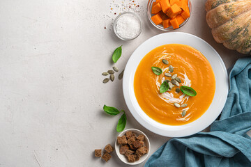 Pumpkin soup with carrots and cream on a gray background with space for copying.