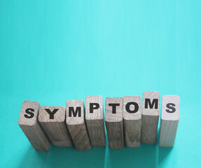Symptoms word from wooden blocks with letters, viral diseases prevention and healing concept, blue...