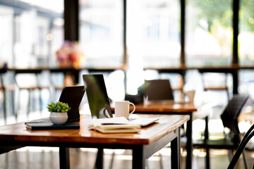 Closeup of tablet and laptop computer note and cup on table in office with nobody blur background.
