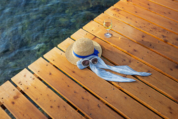Fototapeta na wymiar The concept of a vacation at the sea on a wooden pier is a hat, sunglasses, a glass of wine, top view.