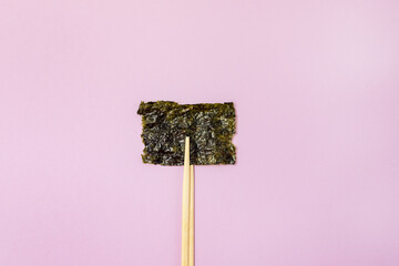 Small Crispy Nori Sheets Pink Background Healthy Japanese Snack Horizontal Bamboo Chopsticks © katekrsk