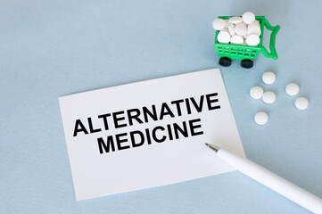 white card with Alternative medicine check text message on a blue background next to scattered white pills, a pen