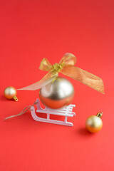 Christmas composition with gold ball on a white toy sleigh on the red background