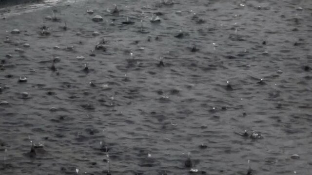 Closeup overcast storm weather raindrops splashing on water surface downpour