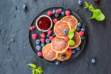 A healthy breakfast of cheese pancakes, berries, and honey. Creative atmospheric decoration