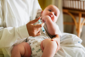 A nurse doctor makes an injection to a child's baby at home in a bedroom, an examination of a baby at home, a patronage. Regular medical examination of babies, preventive vaccinations