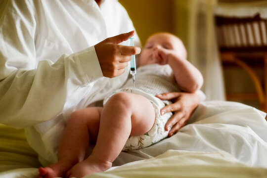 A nurse doctor makes an injection to a child's baby at home in a bedroom, an examination of a baby at home, a patronage. Regular medical examination of babies, preventive vaccinations