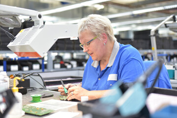 Fototapeta na wymiar friendly woman working in a microelectronics manufacturing factory - component assembly and soldering