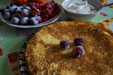 Large pancakes are on the plate. Decorated on top with black currant berries.