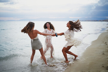 Three women making circle and turning together while laughing and having fun on beach