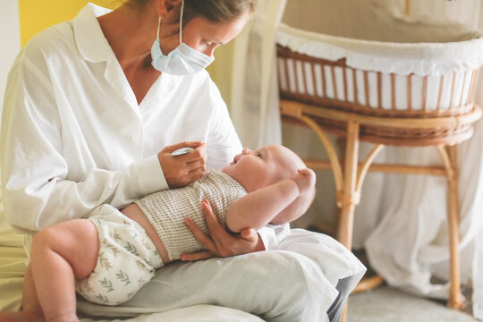Doctor nurse examines the throat of the baby's child at home in the bedroom, examining the baby at home, patronage. Regular medical examination of babies, preventive examination, family doctor