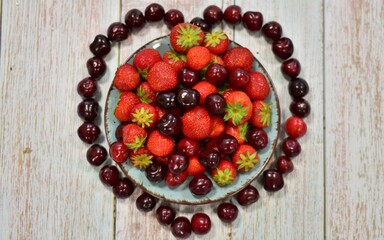 Fototapeta na wymiar ripe strawberries and cherries on a wooden background 