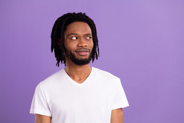 Photo of puzzled minded dark skin young man look empty space good mood isolated on violet color background