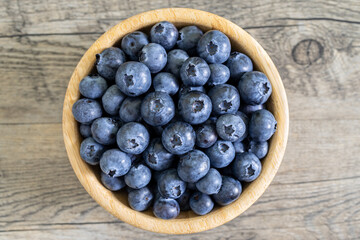 Blueberries in a bamboo bowl on a wooden table. Healthy diet high in antioxidants concept. Highly detailed top view with natural light.