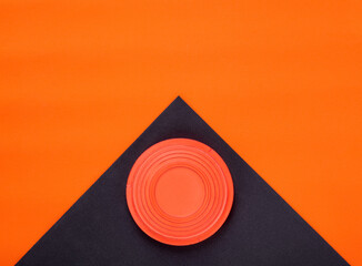 Orange clay target on black and orange geometric background. Skeet shooting. Copy space