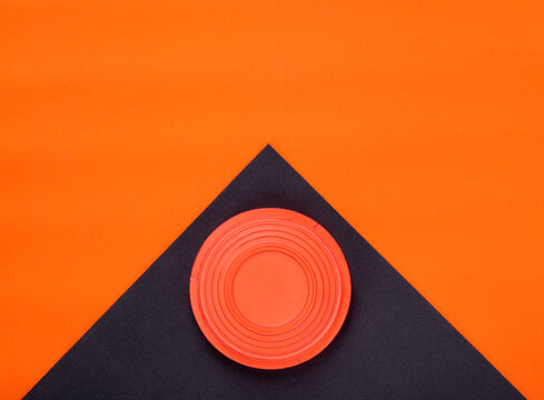 Orange clay target on black and orange geometric background. Skeet shooting. Copy space