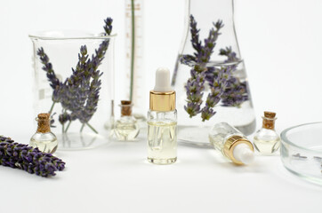 A bottle of lavender oil and medical flasks with lavender flowers on a white background. Moisturizing skin care