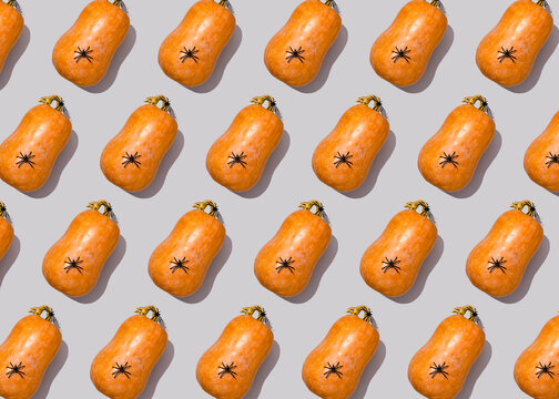 Halloween pattern of spiders sitting on top of raw pumpkins