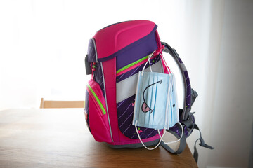 Face masks hanging on backpack at table