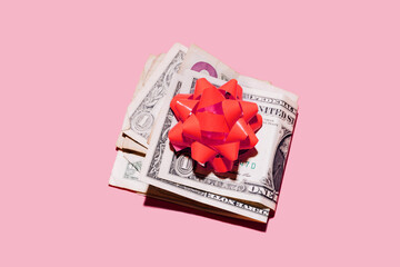 Studio shot of folded dollar bills with red gift bow