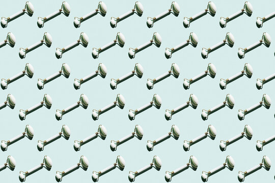 Pattern of marble jade rollers flat laid against mint green background