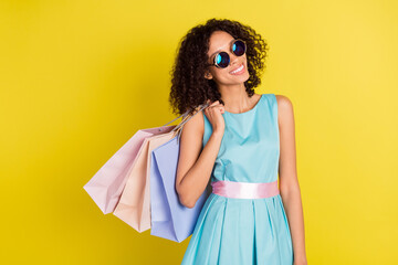 Photo of charming young afro american woman wear sunglass hold shopping bags isolated on yellow color background