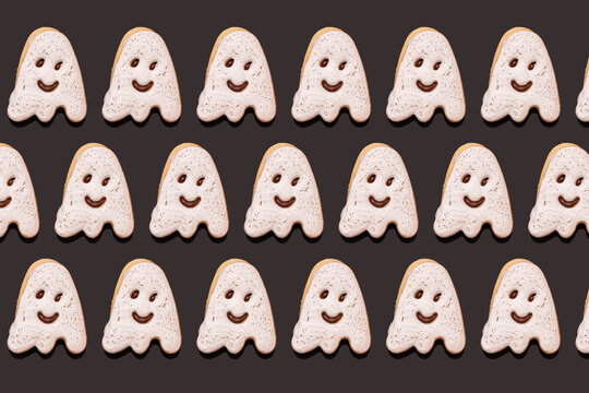 Pattern of ghost-shaped chocolate cookies flat laid against black background