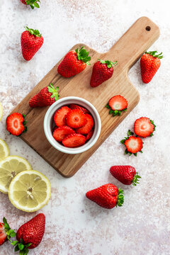 Cutting board, fresh ripe strawberries and sliced lemon