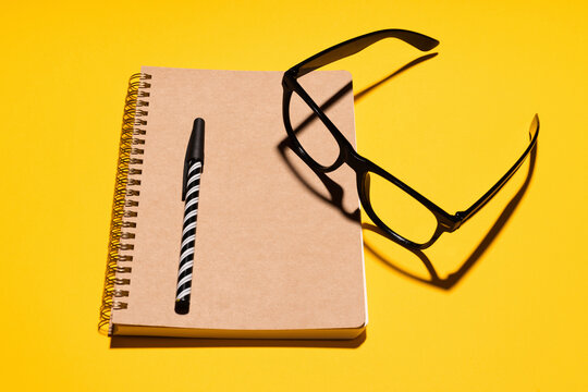 Studio shot of eyeglasses, pen and note pad from recycled paper