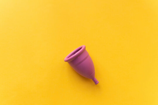 Menstrual cup against bright yellow background
