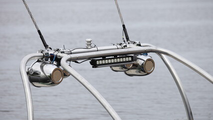 Close up chrome tower boat Targa top with speakers and flash light, a pole for towing water-skiing on a motor boat for wake riding at summer day against water background, outdoor watersports activity
