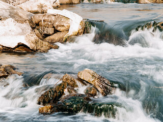 Fototapeta na wymiar the flow of a stormy river over rocks, clear blue water