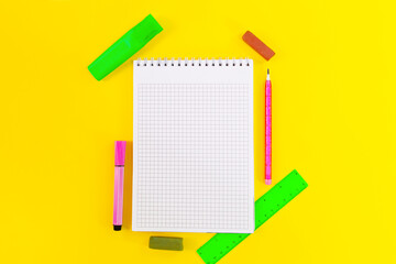 Back to school. Education. Notebook cell for notes, markers, crayons, pencil, ruler on yellow background. Flat lay. Copy space