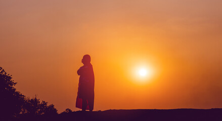 Obraz premium super hero silhouette The boy stood still, calmly meditating. The back gate is lit by the setting sun. silhouette concept