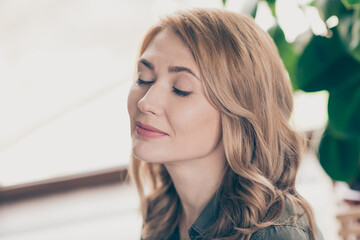 Portrait of attractive dreamy peaceful wavy-haired woman enjoying being lonely staying at home house flat indoors