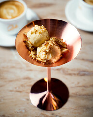 Tea flavored ice cream in copper bowl, coffee on marble table
