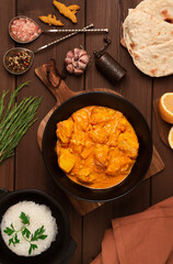 Chicken curry with rice and chapati flatbread, a traditional Indian dish, on a wooden table, no people, selective focus,