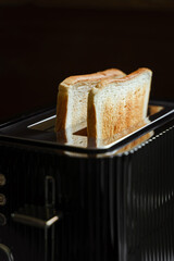 Toasted bread popping up from a black retro toaster